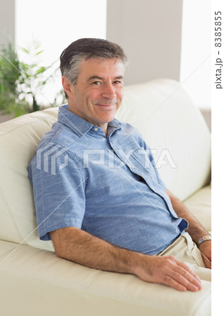 Smiling man sitting on a sofa 8385855