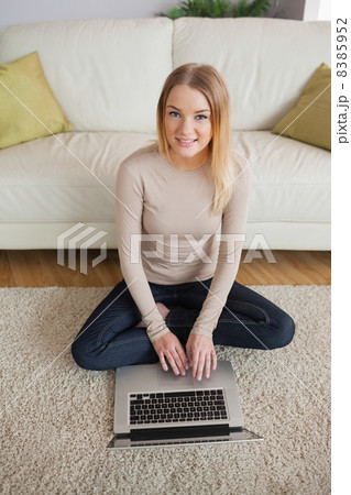 Happy woman sitting on floor using laptop 8385952