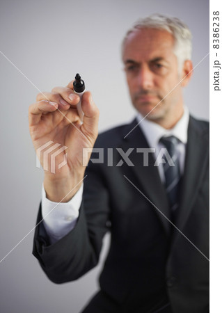 Serious businessman holding a marker and writing Serious businessman holding a marker and writing 8386238