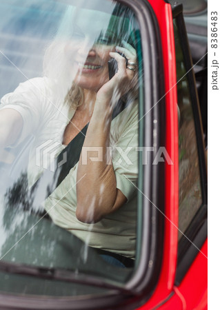 Smiling mature woman on the phone driving red cabriolet 8386483
