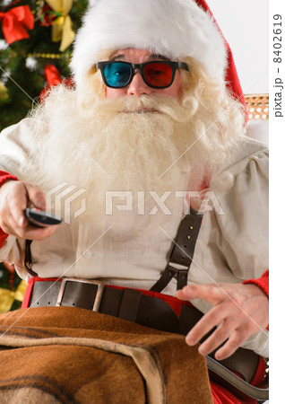 Santa Claus sitting in rocking chair near Christmas Tree at home 8402619