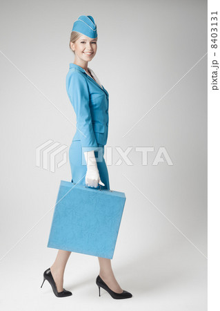 Charming Stewardess Dressed In Blue Uniform And Suitcase On Gray Charming Stewardess Dressed In Blue Uniform And Suitcase On Gray 8403131