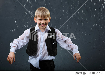 smiling boy dressed in wet white shirt and black vest stands in 8403445