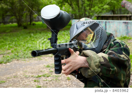 Paintball player in camouflage uniform and protective mask with 8403962