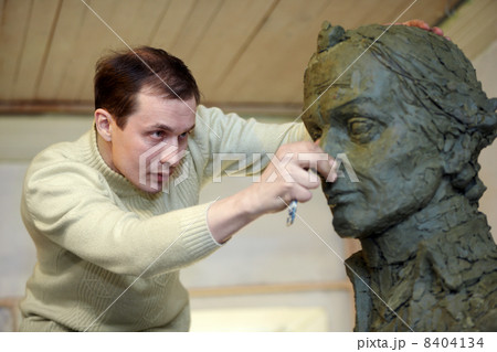 Sculptor works in the studio with a plasticine model of the bust 8404134