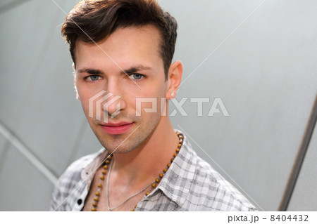 Young beautiful man stands near gray wall and looks at camera 8404432