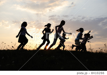 Silhouette, group of happy children playing on meadow, sunset, summertime 8410266