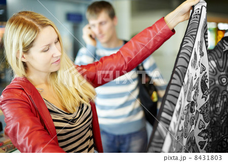 Young woman in red leather jacket considers colorful fabric Young woman in red leather jacket considers colorful fabric 8431803
