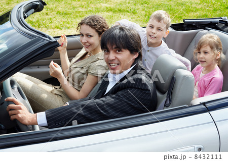 Family of four sits in the open top car, focus on the driver in Family of four sits in the open top car, focus on the driver in 8432111