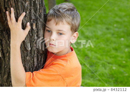 Portrait of boy in orange t-shirt, that stands, embracing tree i Portrait of boy in orange t-shirt, that stands, embracing tree i 8432112