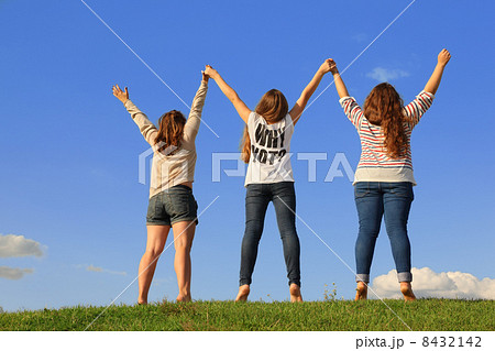 Back of three girls holding hands at green grass at background o Back of three girls holding hands at green grass at background o 8432142