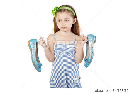 Pensive girl in striped sundress stands, holding big mother shoe Pensive girl in striped sundress stands, holding big mother shoe 8432339