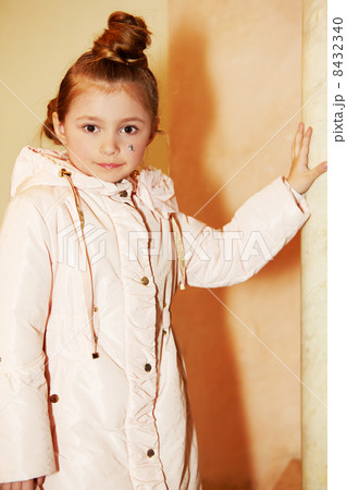 Girl in light coat stands, leaning one hand on marble pillar Girl in light coat stands, leaning one hand on marble pillar 8432340