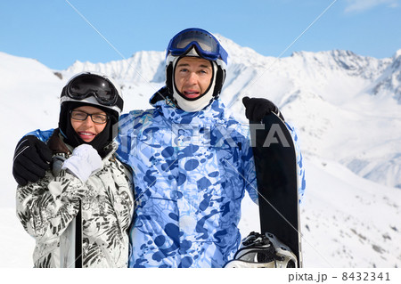Smiling couple in sport suits and helmets stand with snowboard a Smiling couple in sport suits and helmets stand with snowboard a 8432341
