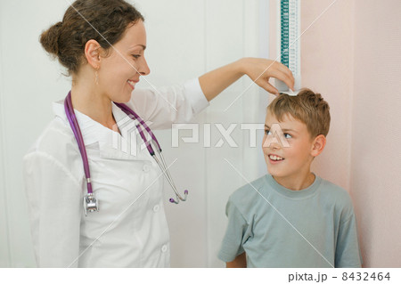Doctor measures growth smiling boy in medical office, focus on doctor 8432464