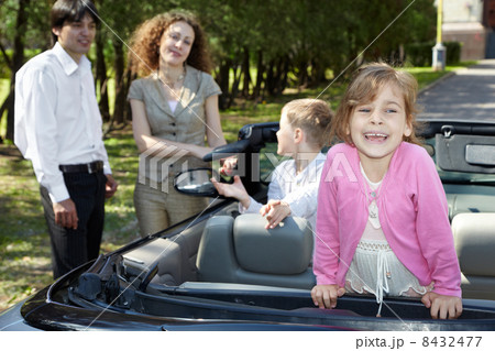 Little girl stands on backseat in cabriolet and laughs, parents Little girl stands on backseat in cabriolet and laughs, parents 8432477