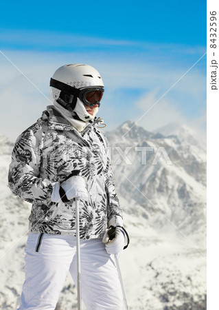 Young woman in ski suit and in helmet stands on background of mo 8432596