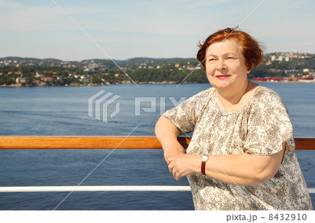Elderly woman stands at board of ship near railing and looks int Elderly woman stands at board of ship near railing and looks int 8432910