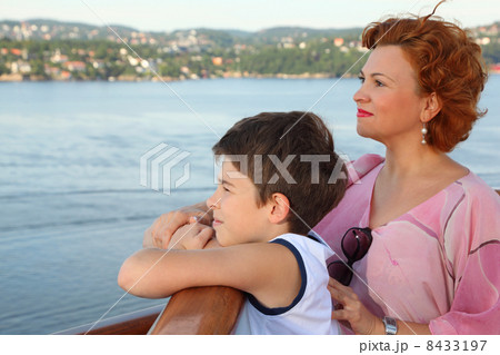 Mother and son are on board of ship and look at beautiful landsc 8433197