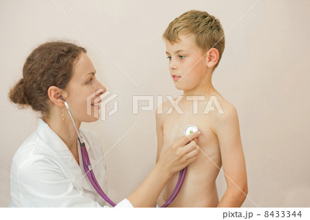 Smiling doctor listens to lungs of little boy with stethoscope, focus on boy 8433344