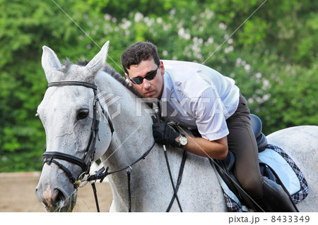 Jockey in glasses with whip hug horse on hippodrome Jockey in glasses with whip hug horse on hippodrome 8433349