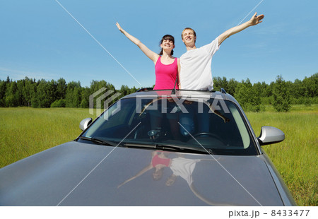 Husband, wife pose in hatch of car before hood in field 8433477