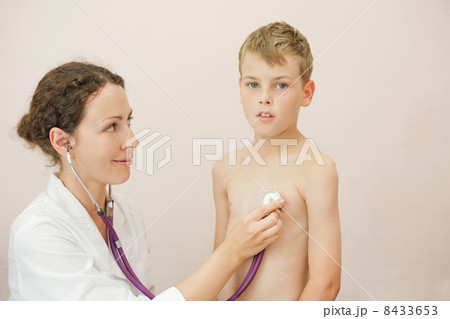Doctor listens to lungs of little boy with stethoscope looks at him 8433653