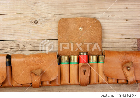 Old hunting cartridges and bandoleer on a wooden table Old hunting cartridges and bandoleer on a wooden table 8436207