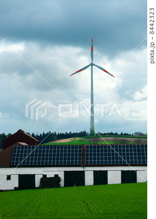 solar energy panels at the countryside house and wind turbine in field 8442323