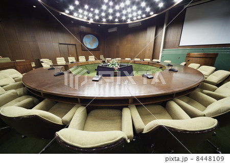 Auditorium with round oak table, beige armchairs around it, whit 8448109