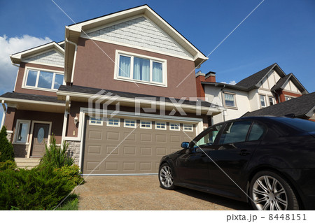 Car near the garage of new two-storied brown cottage with white 8448151