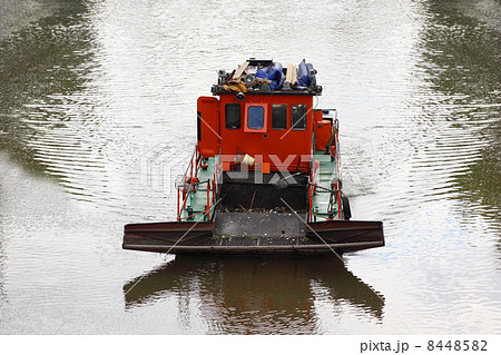 small red boat floats down river and clean river of debris, clea 8448582