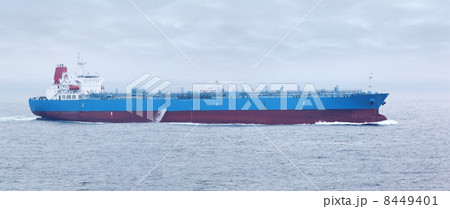 Large cargo ship with red and blue boards floats in open ocean 8449401