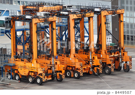 Many empty large orange loaders stand on asphalt in seaport 8449507
