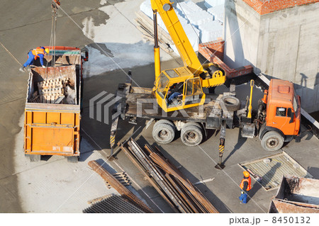 Crane loads garbage into truck at construction site. Building ma Crane loads garbage into truck at construction site. Building ma 8450132