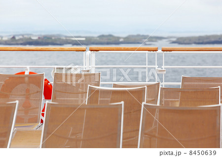 Many sun loungers are on deck of ship. Seashore is seen in dista Many sun loungers are on deck of ship. Seashore is seen in dista 8450639