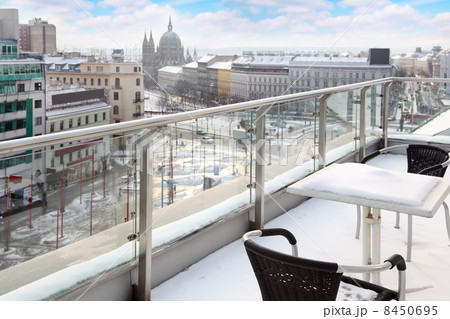 Table and chairs on balcony in snow at winter day. View of city. Table and chairs on balcony in snow at winter day. View of city. 8450695