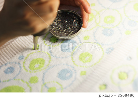 Woman glueing sequins to colorful fabrics 8509490