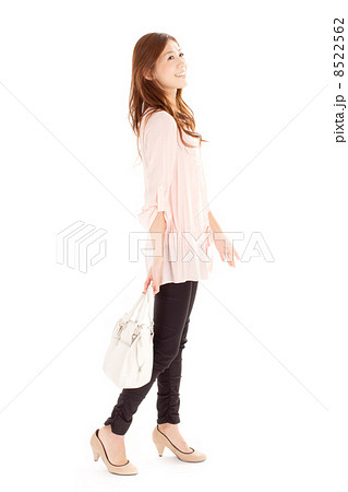 ハンドバッグを手に持ち楽しそうに歩くミドルの格好いい女性の写真素材