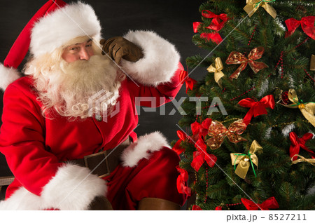 Santa Claus standing near Christmas tree in dark room Santa Claus standing near Christmas tree in dark room 8527211