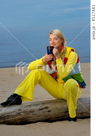 Beautiful woman drinking hot tea on the beach Beautiful woman drinking hot tea on the beach 8527881