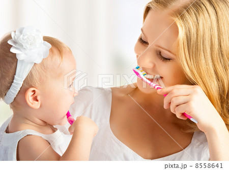 mother and daughter baby girl brushing their teeth together mother and daughter baby girl brushing their teeth together 8558641