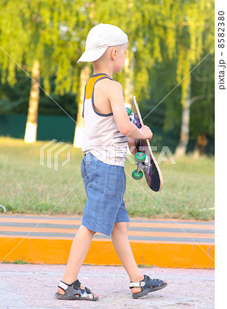 Boy Child going with Skateboard behind view Outdoor Summer Sport with nature on background Boy Child going with Skateboard behind view Outdoor Summer Sport with nature on background 8582380