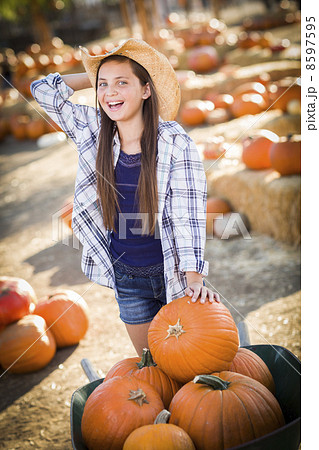 Preteen Girl Playing with a Wheelbarrow at the Pumpkin Patch. Preteen Girl Playing with a Wheelbarrow at the Pumpkin Patch. 8597595