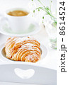 Croissant with coffee, on sunlit breakfast tray 8614524