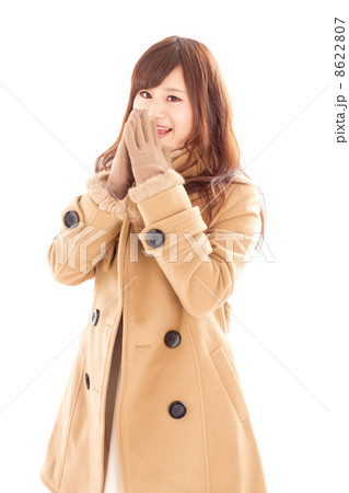 寒そうに手袋をして顔の前で手を合わせる可愛らしい女の子の写真素材
