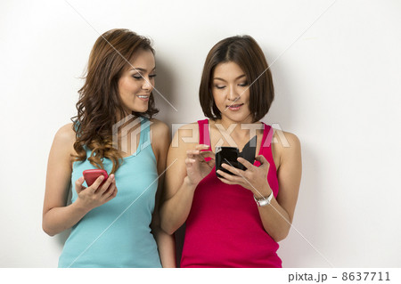 Two happy Asian women using there smartphones. 8637711