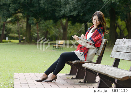 公園のベンチに座って絵を描く若い女性の写真素材
