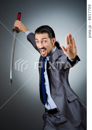 Angry businessman with sword in dark room Angry businessman with sword in dark room 8657709
