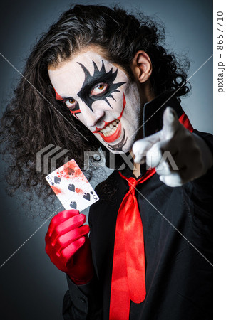 Evil clown with cards in dark room 8657710